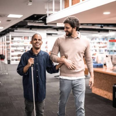 Mid adult man visually impaired talking with friend at university