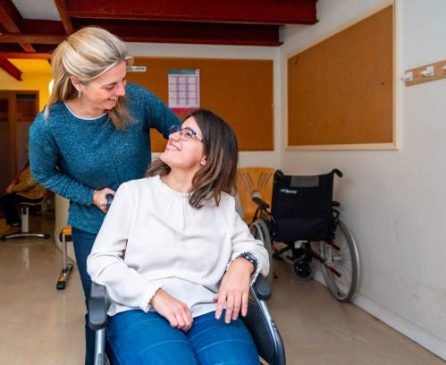 Caregiver pushing the wheelchair of a disabled woman in a day center for people with special needs